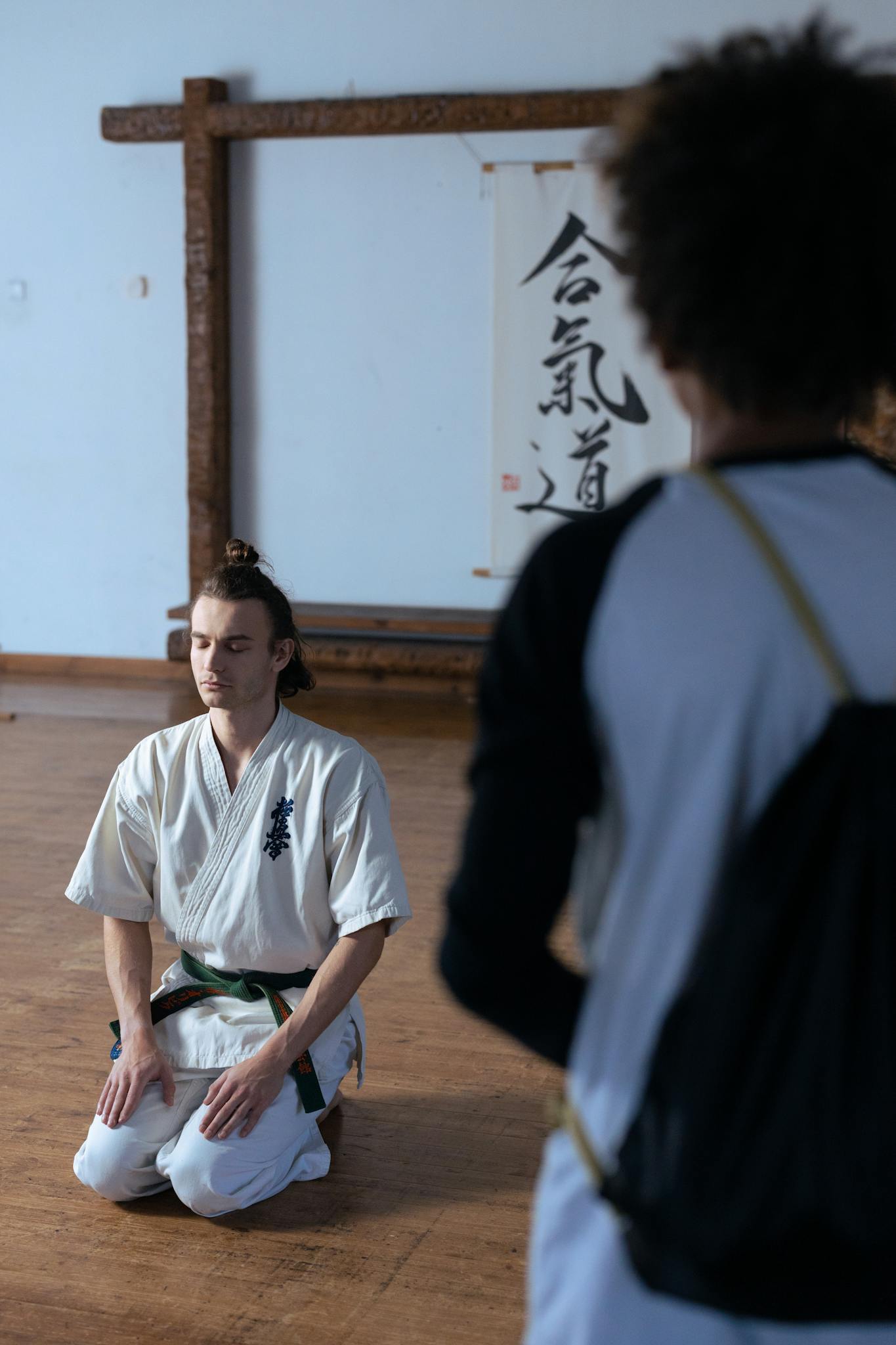 Martial artist kneeling and meditating inside a dojo, focusing on mindfulness and discipline.