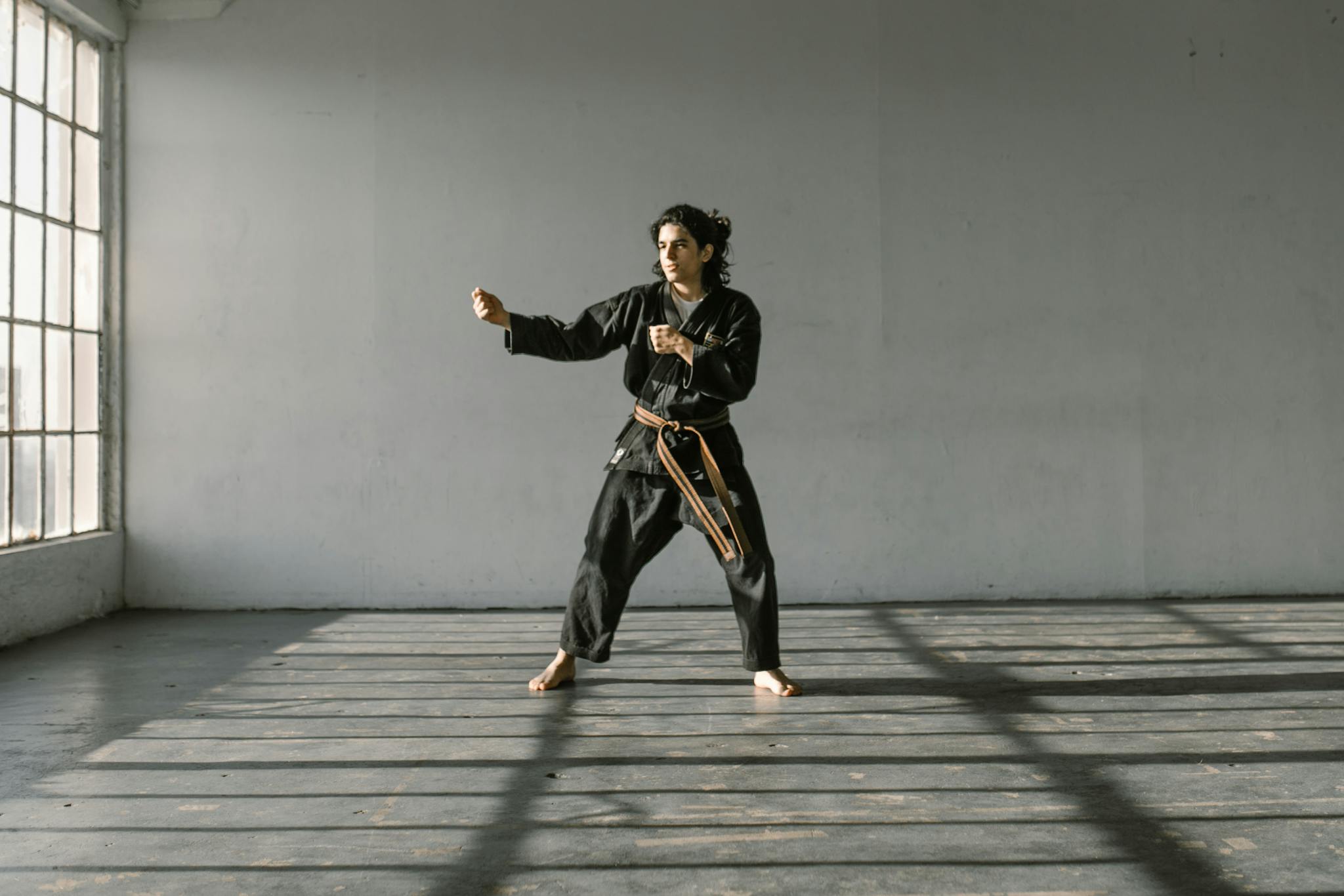 Martial artist performs a kata in a well-lit dojo, emphasizing strength and focus.